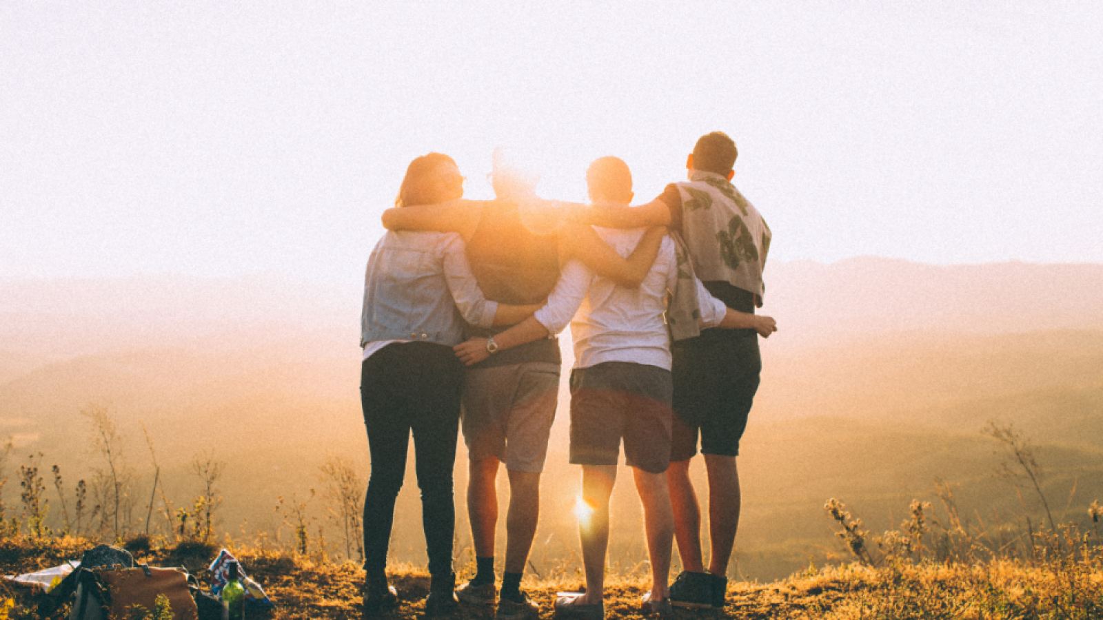 Grupo de amigos abrazados al atardecer